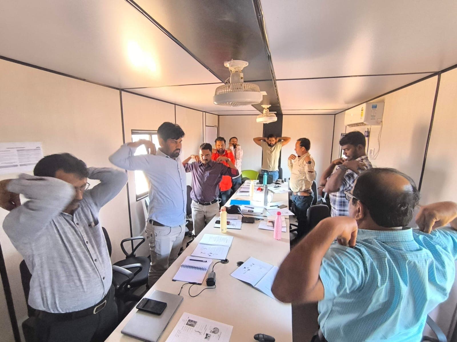 Employees doing a stretching exercise at their desks during an Eduforce ergonomics and wellbeing session