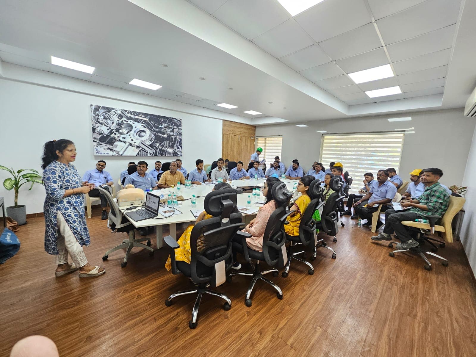 Eduforce instructor leading a first aid training session for employees around a long table in a modern office meeting room