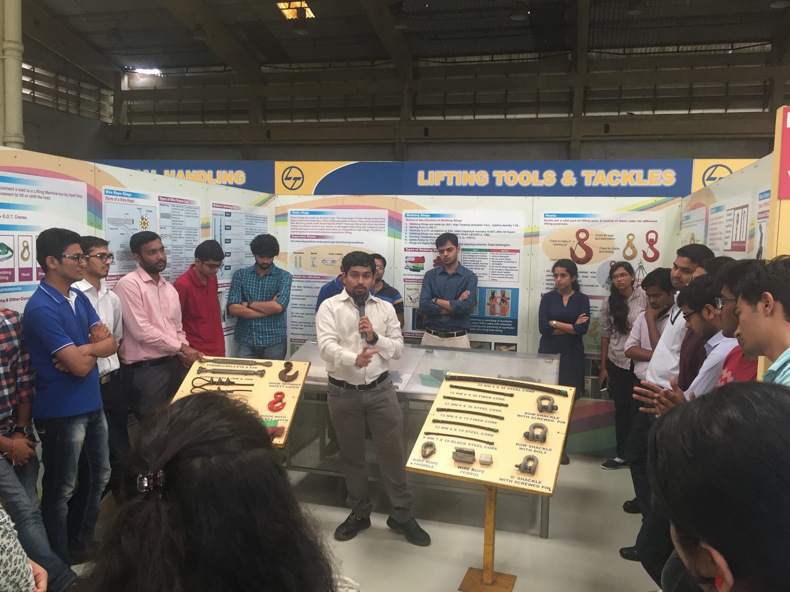 Instructor explaining lifting tools and tackles — slings, shackles and hooks — on a display board to trainees