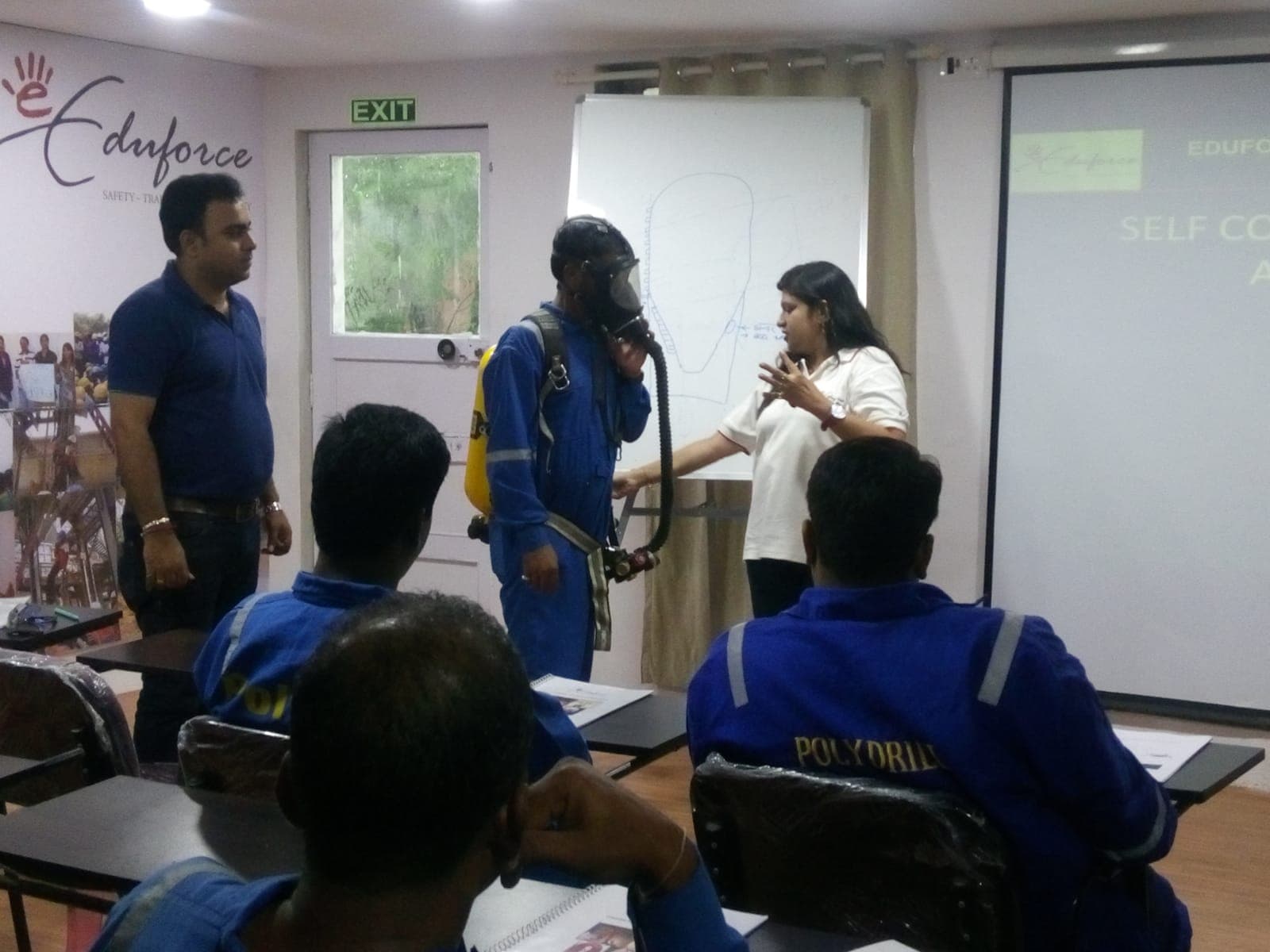 Trainee wearing a self-contained breathing apparatus face mask while the instructor explains it to the class