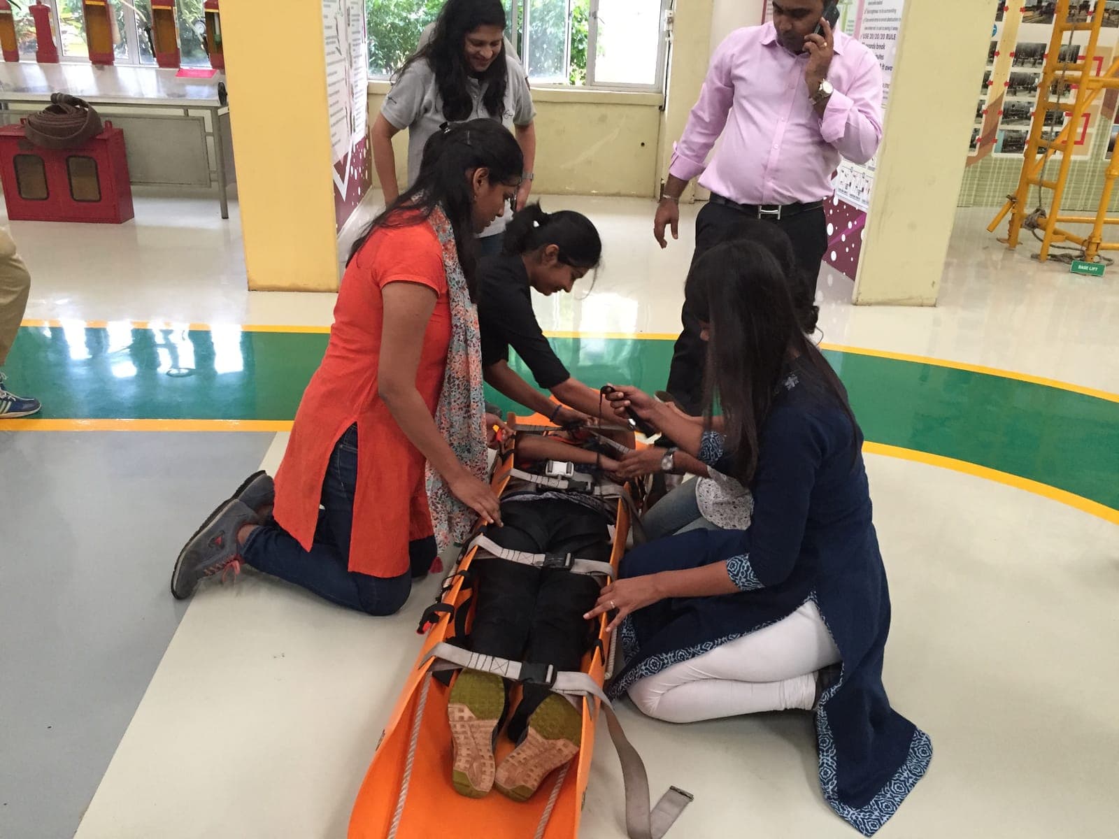 Trainees strapping a casualty to a spine board to immobilise him during a trauma care practical