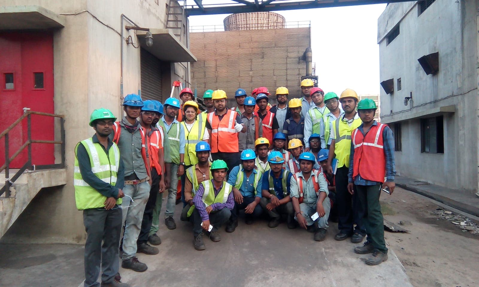 Group of workers in hard hats and high-visibility vests at an industrial plant after safety training