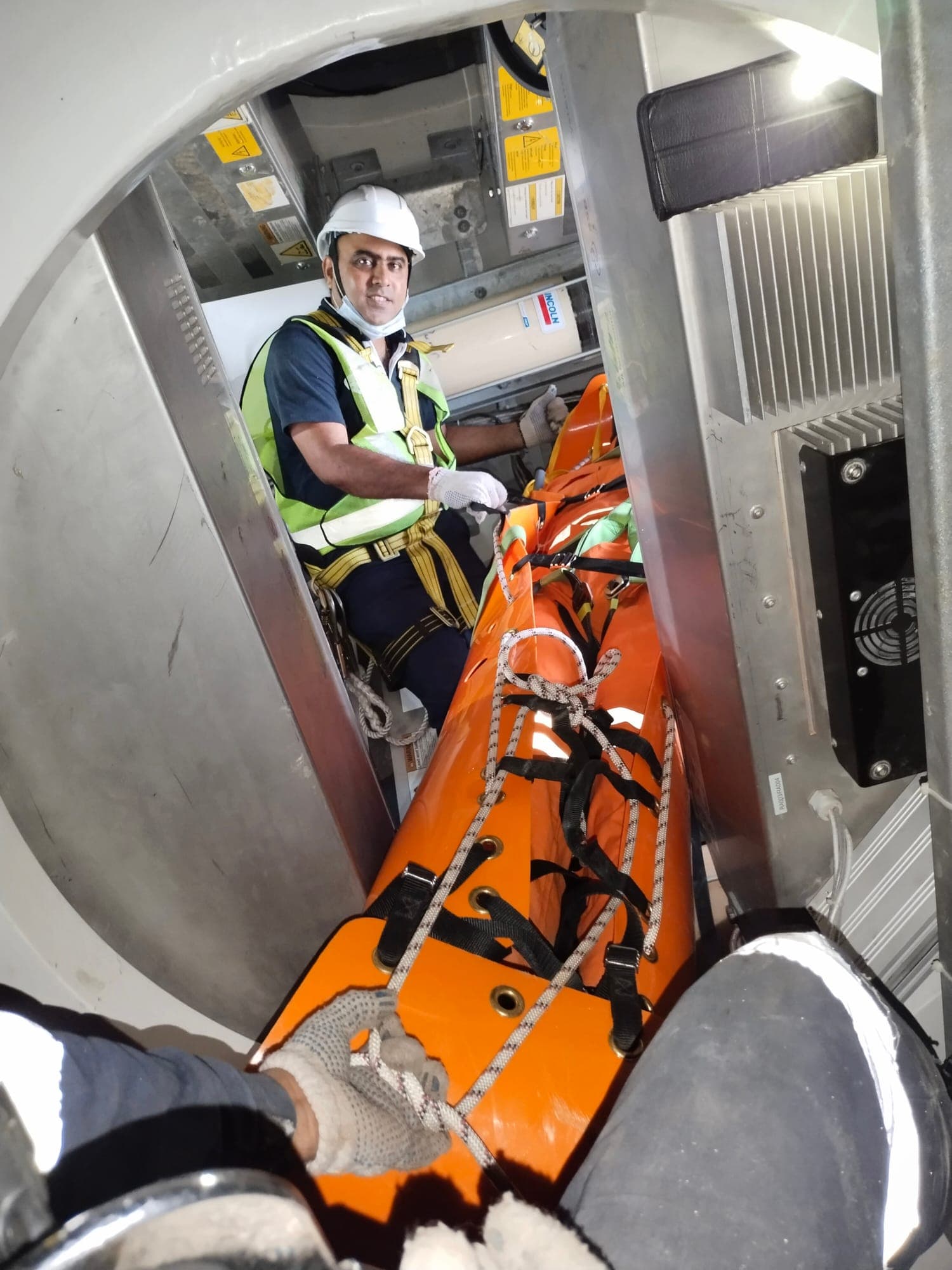 Rescuer with an orange basket stretcher inside a wind turbine service area during advanced rescue training
