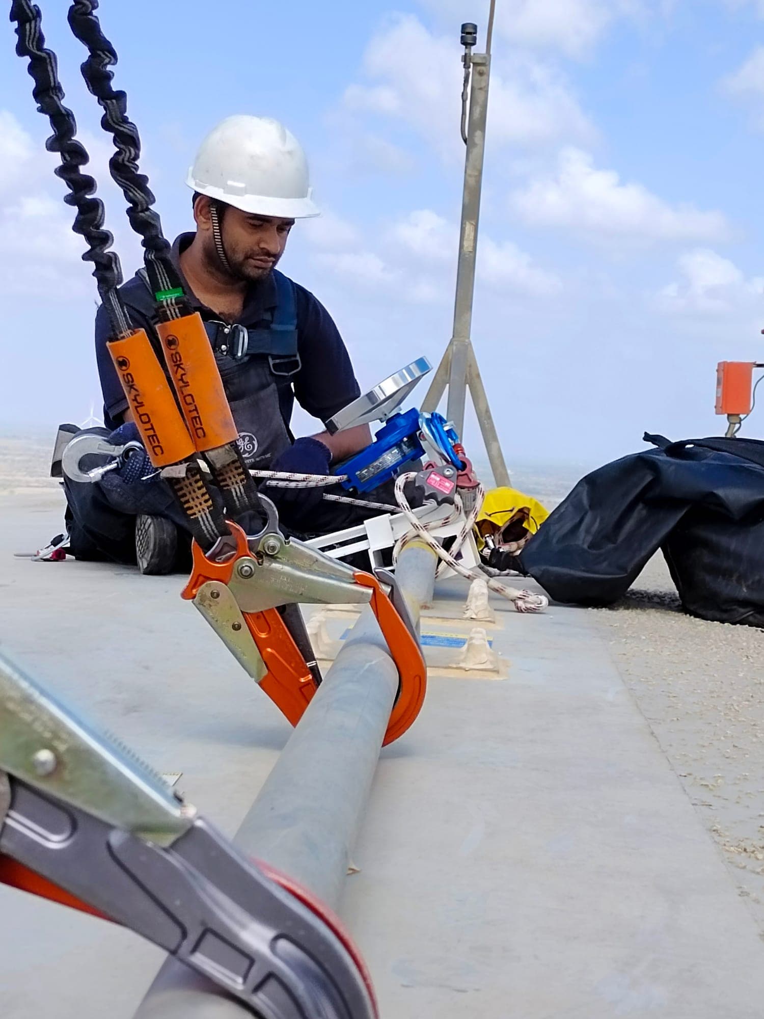 Technician preparing a rescue stretcher rigged to a line on a wind turbine nacelle roof