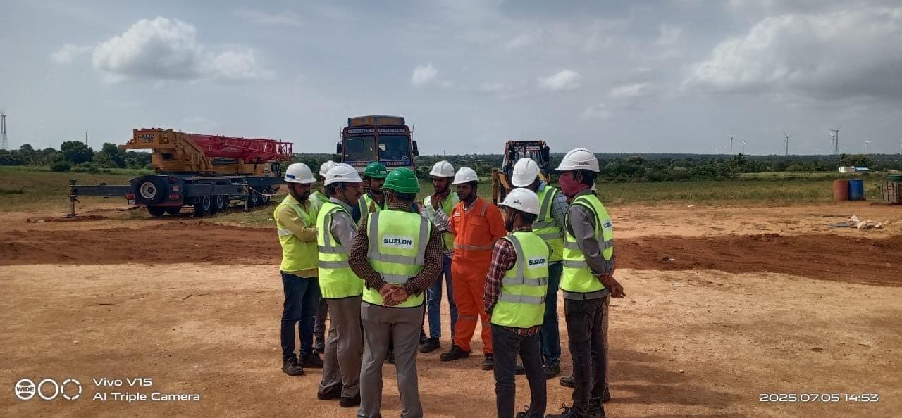 Trainer and participants in high-visibility vests during a site walkdown with lifting equipment behind