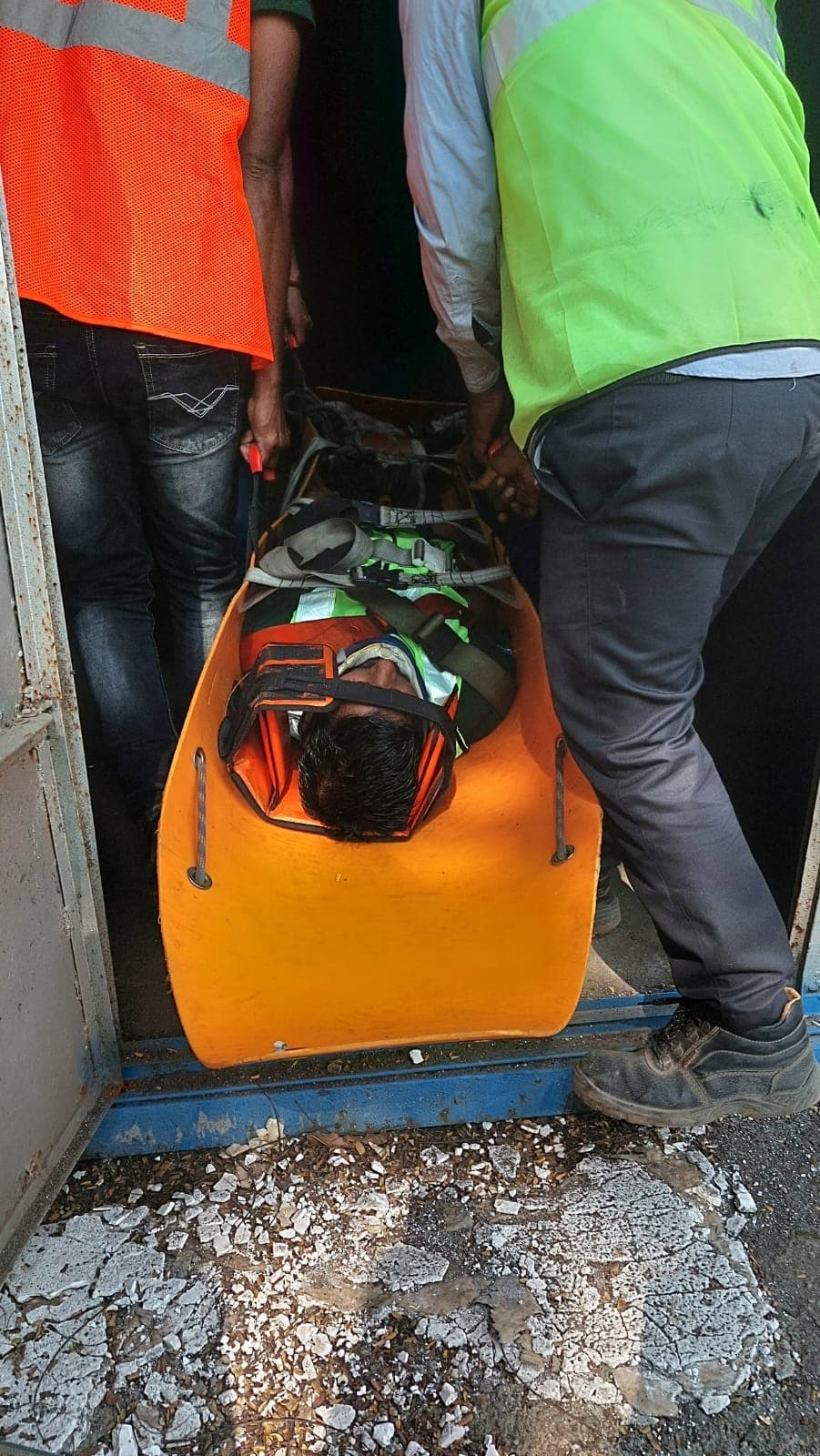 Team carrying a volunteer casualty on a stretcher through a doorway during a rescue drill