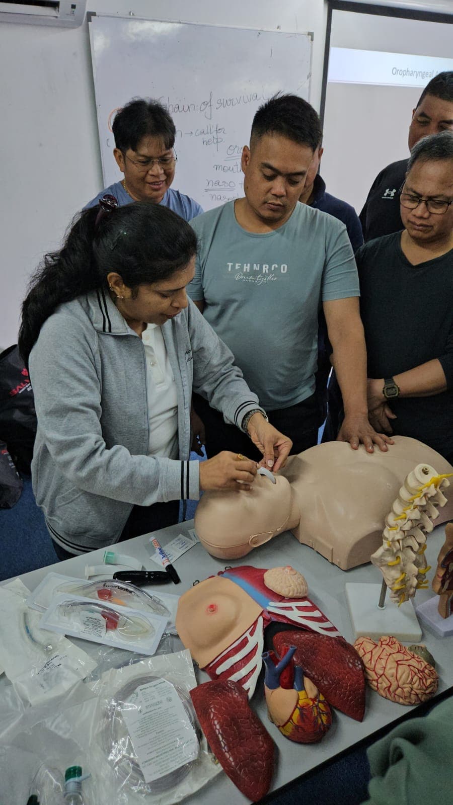 Participants practising airway management on a training manikin with anatomical models alongside