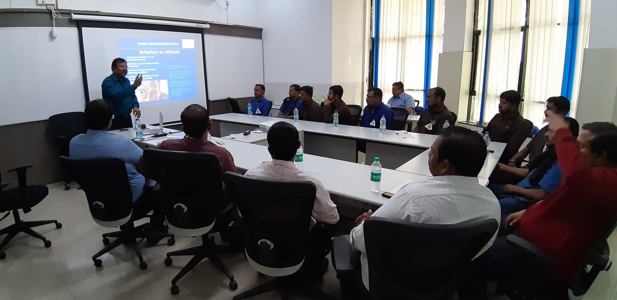Facilitator leading a behaviour based safety session with participants seated around a boardroom table