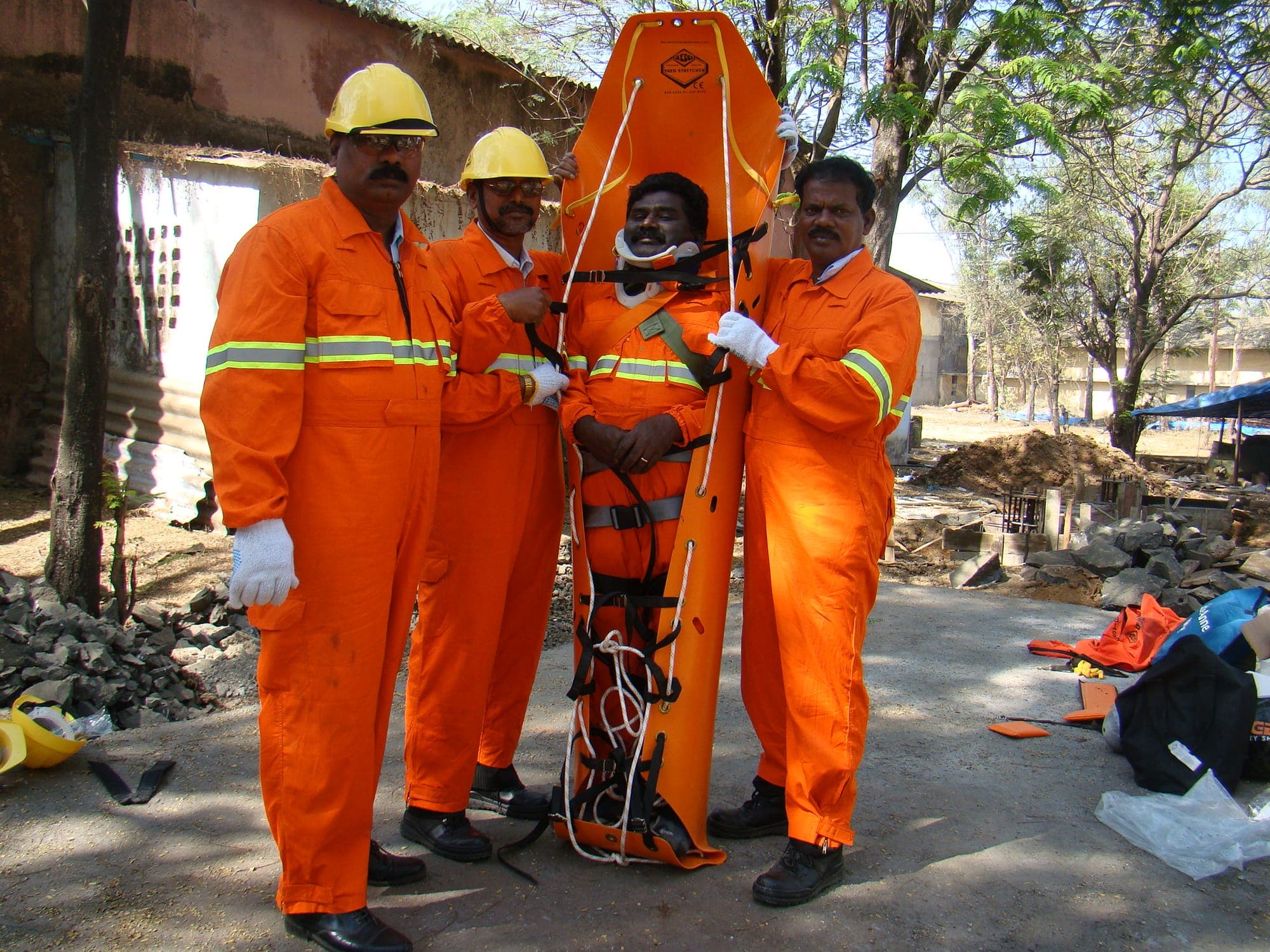 Trainees raising a spine board to the vertical with a casualty secured, supported on both sides