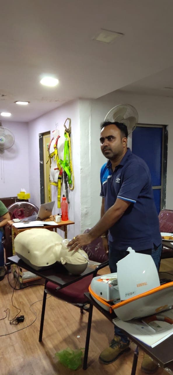 Instructor demonstrating chest compressions on a CPR manikin to a group of participants