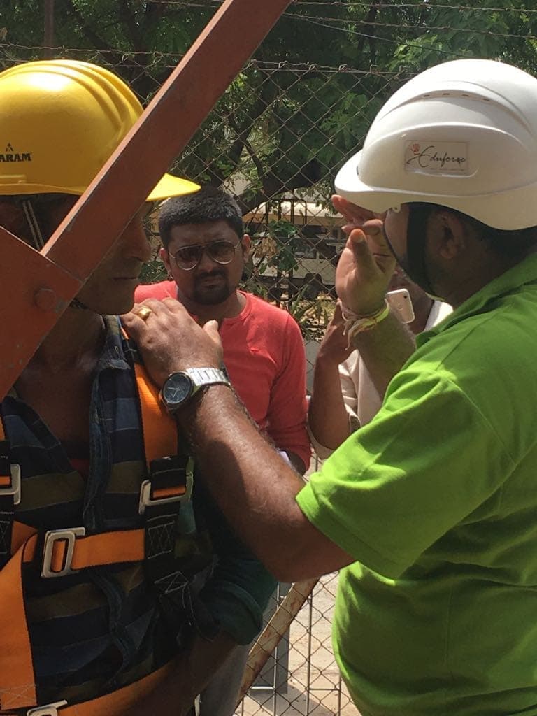 Trainers checking the fit of a participant's full-body harness before a practical