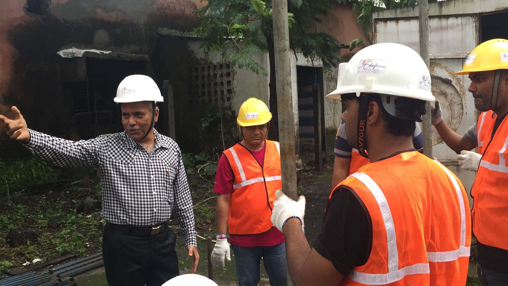 Instructor explaining a scaffold component to participants wearing hard hats and high visibility vests