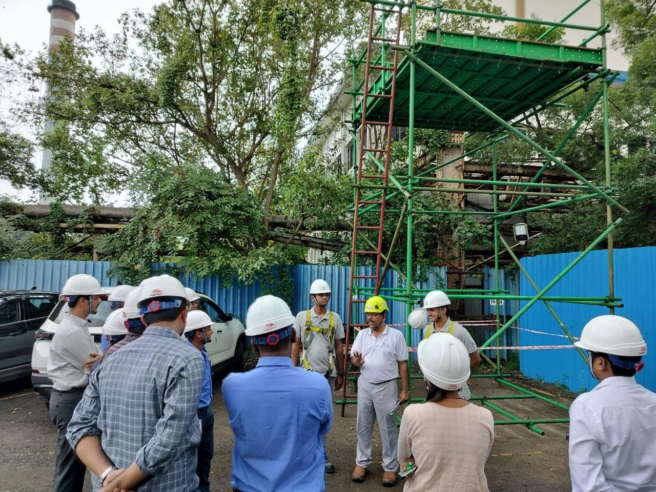 Group of participants in helmets receiving a briefing in front of an erected scaffold