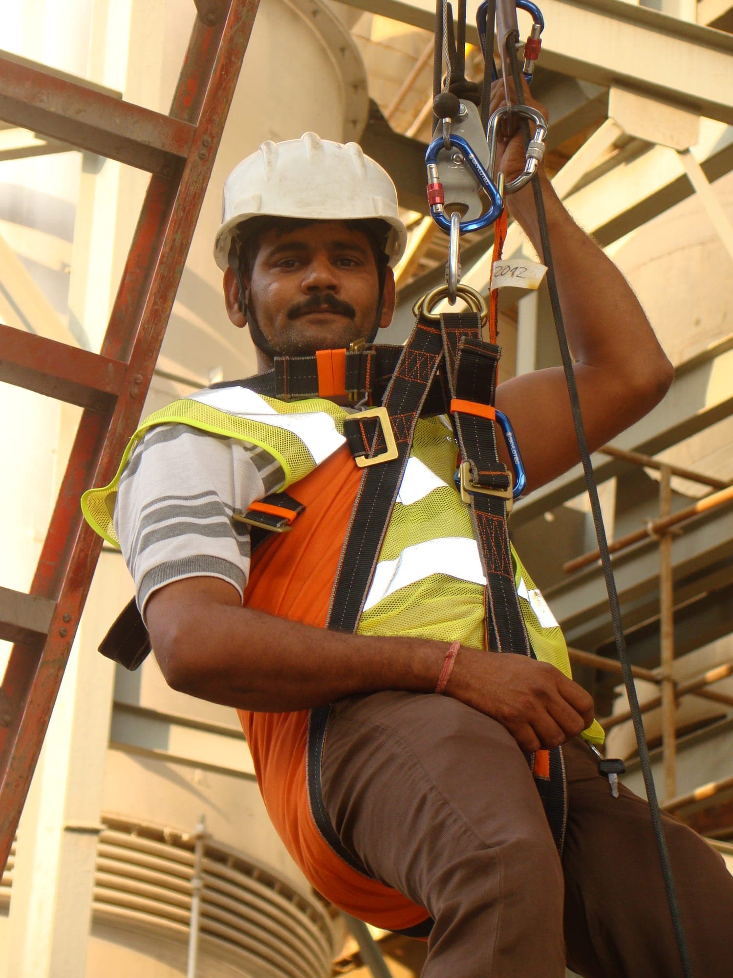 Participant in a hard hat and high visibility vest suspended in a full body harness during a practical exercise