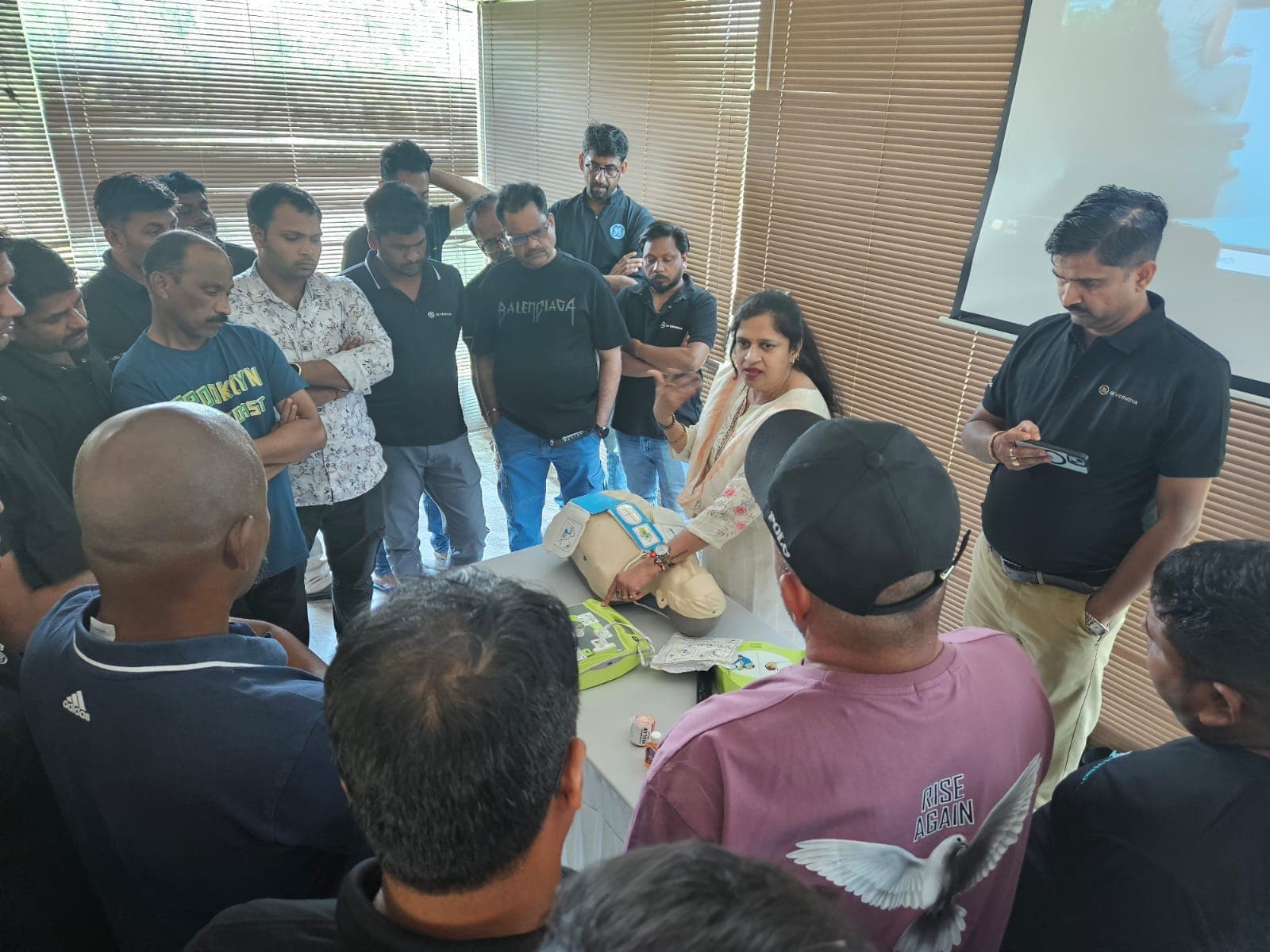 Participants gathered round a CPR manikin while an Eduforce trainer demonstrates during a first aid course