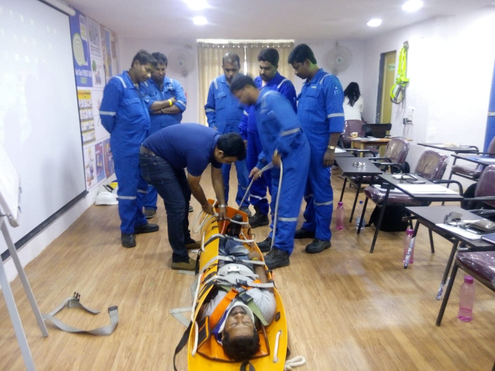 Rescue team in coveralls packaging a casualty in a rescue stretcher during an emergency response drill